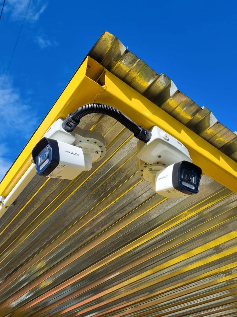 Two Hikvision security cameras installed beneath a corrugated canopy